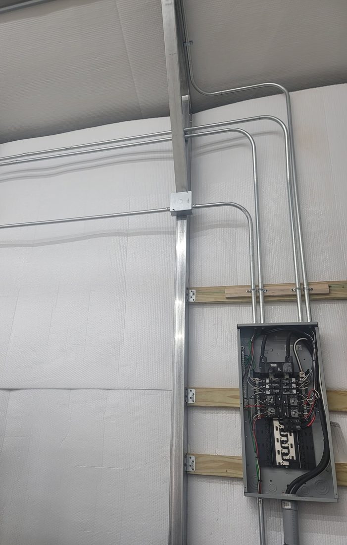 New panel and surface conduit installed in a metal workshop